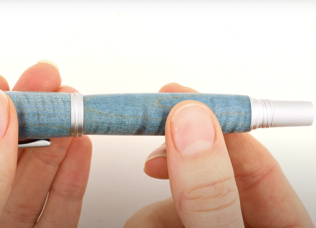 Lower end of an algonquin rollerball pen kit from William Wood-Write made with stabilized curly maple electric blue pen blank.