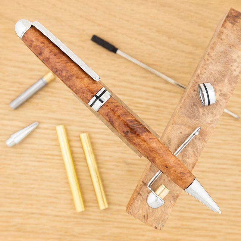 Chrome Budget European round top pen kit from William Wood-Write Ltd turned with red mallee burl pen blank, with unassembled pen kit parts behind it.