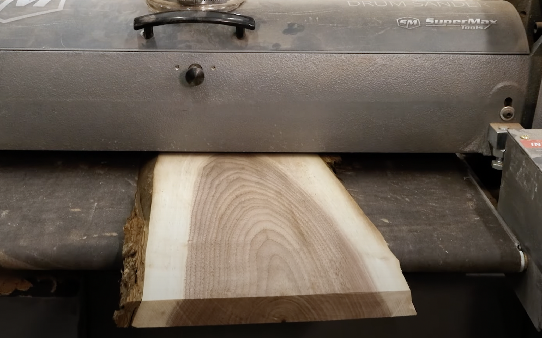 Live edge black walnut charcuterie board from William Wood-Write Ltd. being inserted into wood planer.