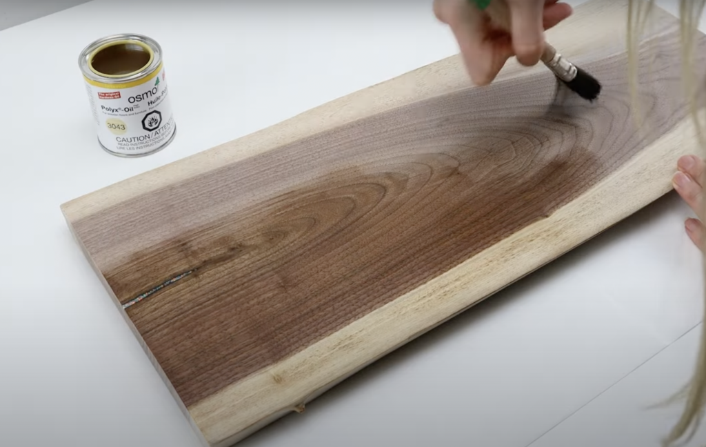 Applying Osmo food-safe poly-oil wood finish wax in clear satin to a black walnut charcuterie board using an osmo natural bristle brush from William Wood-Write Ltd.