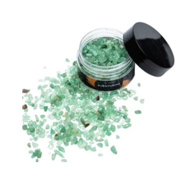 A round container full of crushed green aventurine crystals with some scattered to the side.