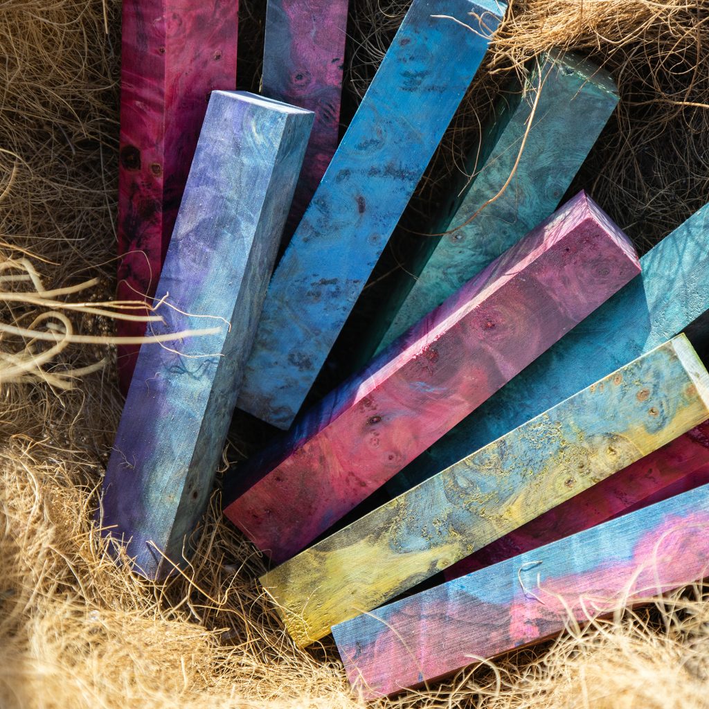 A display of nIne multicoloured pen blanks made from buckeye burl that have been stabilized and dyed.