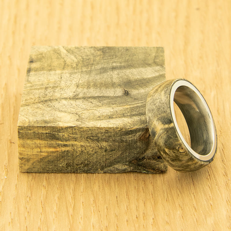 A ring made from stabilized buckeye burl rests against a block of wood.