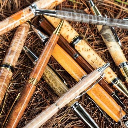 A variety of custom pens made of various kinds of wood on a lathe