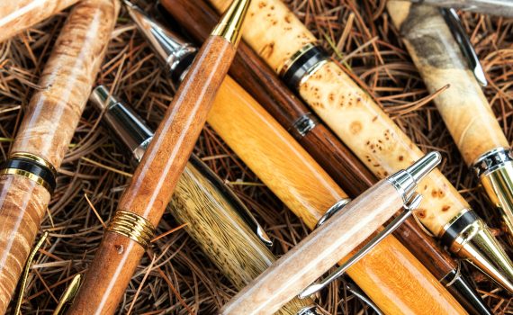 A variety of custom pens made of various kinds of wood on a lathe