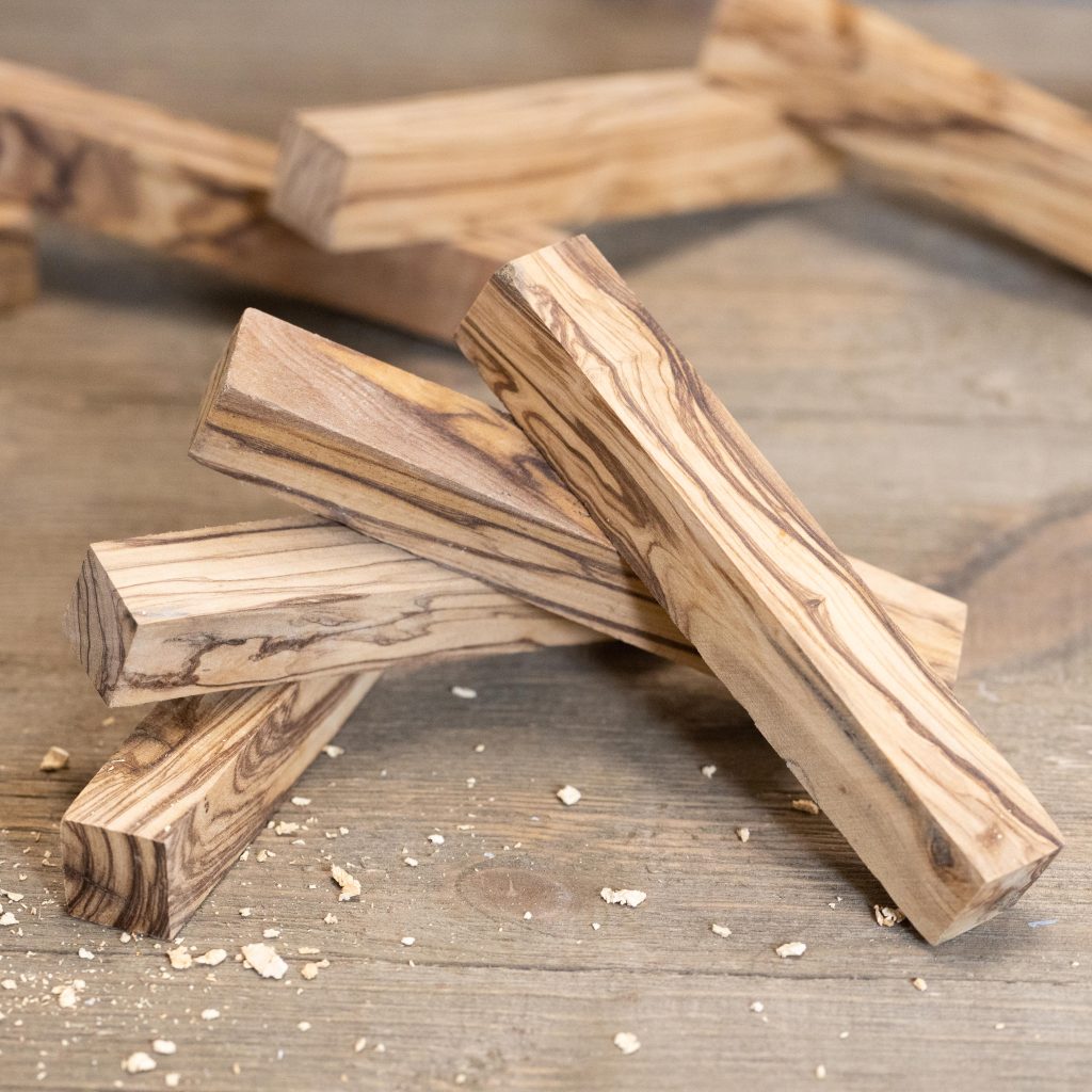 Four pen blanks made of olive wood arranged in a fan shape.