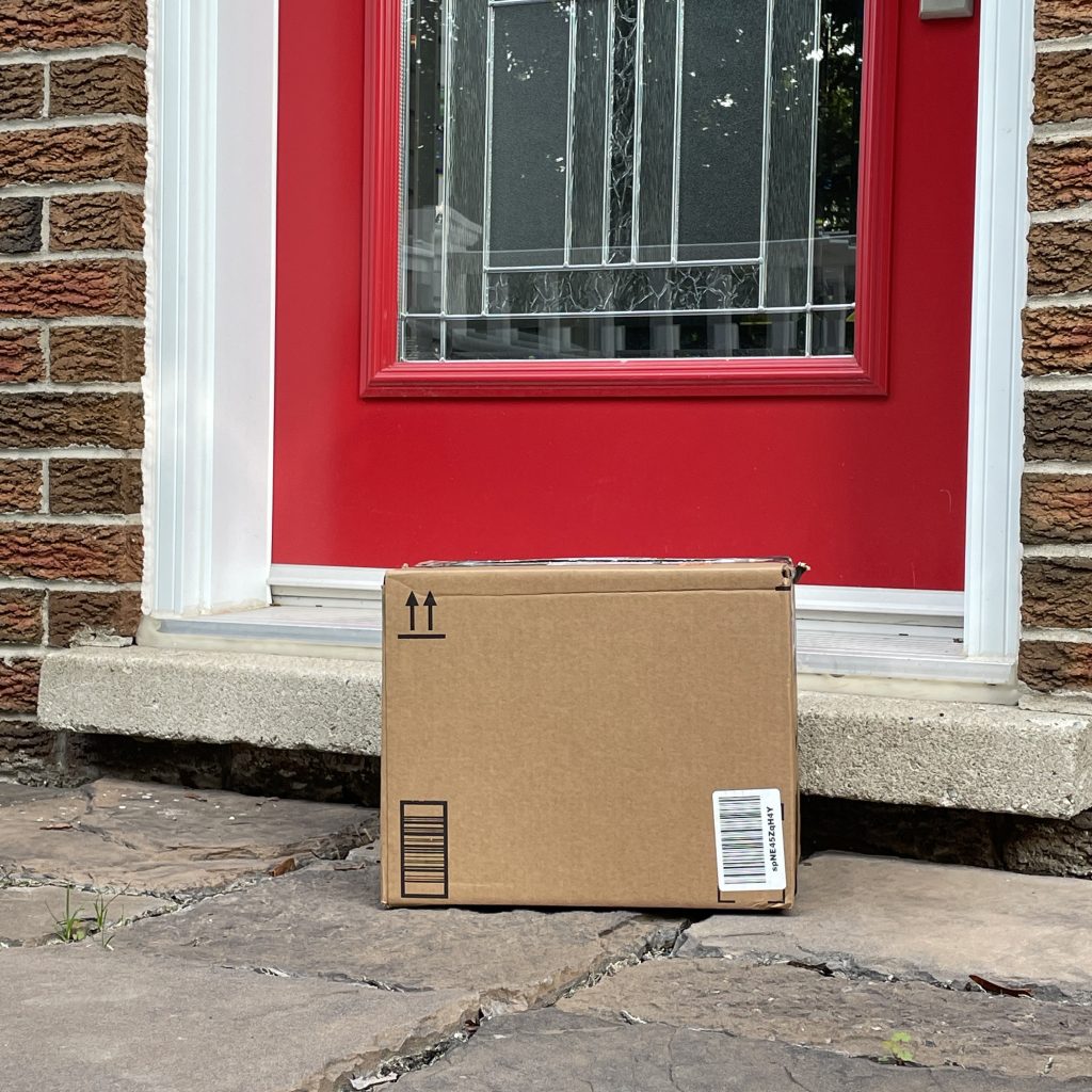 A cardboard box sitting on a porch in front of a red door