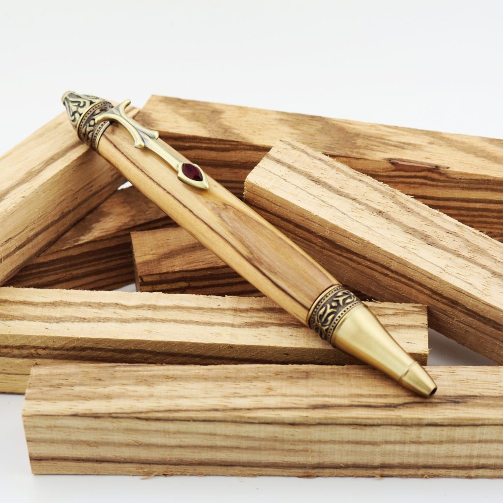 Wood turned handmade pen made of zebra wood sitting on a pile of zebra wood pen blanks.