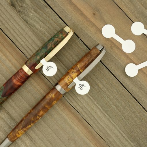 Two wood turned pens laying on weathered wood with price tags showing