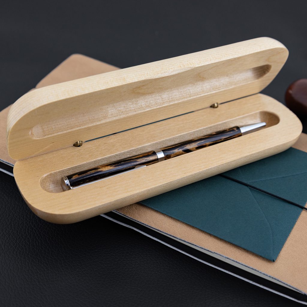 A wooden maple box opened to show a handmade wood turned pen inside