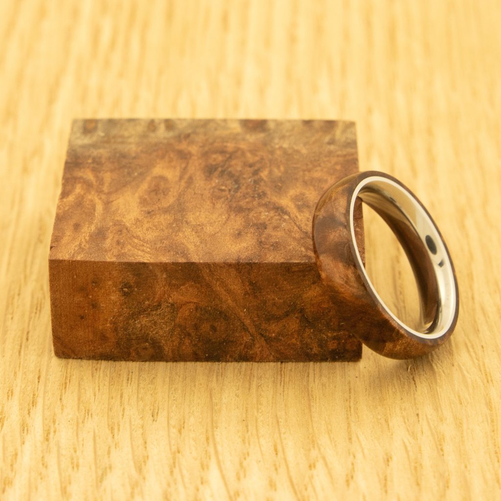 A block of redwood lace burl with a handmade wooden ring leaned against it