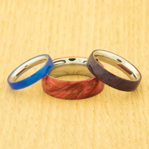 Three handmade wooden rings leaning on one another in blue, red and brown