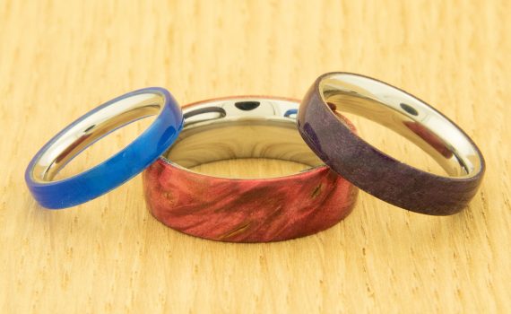 Three handmade wooden rings leaning on one another in blue, red and brown