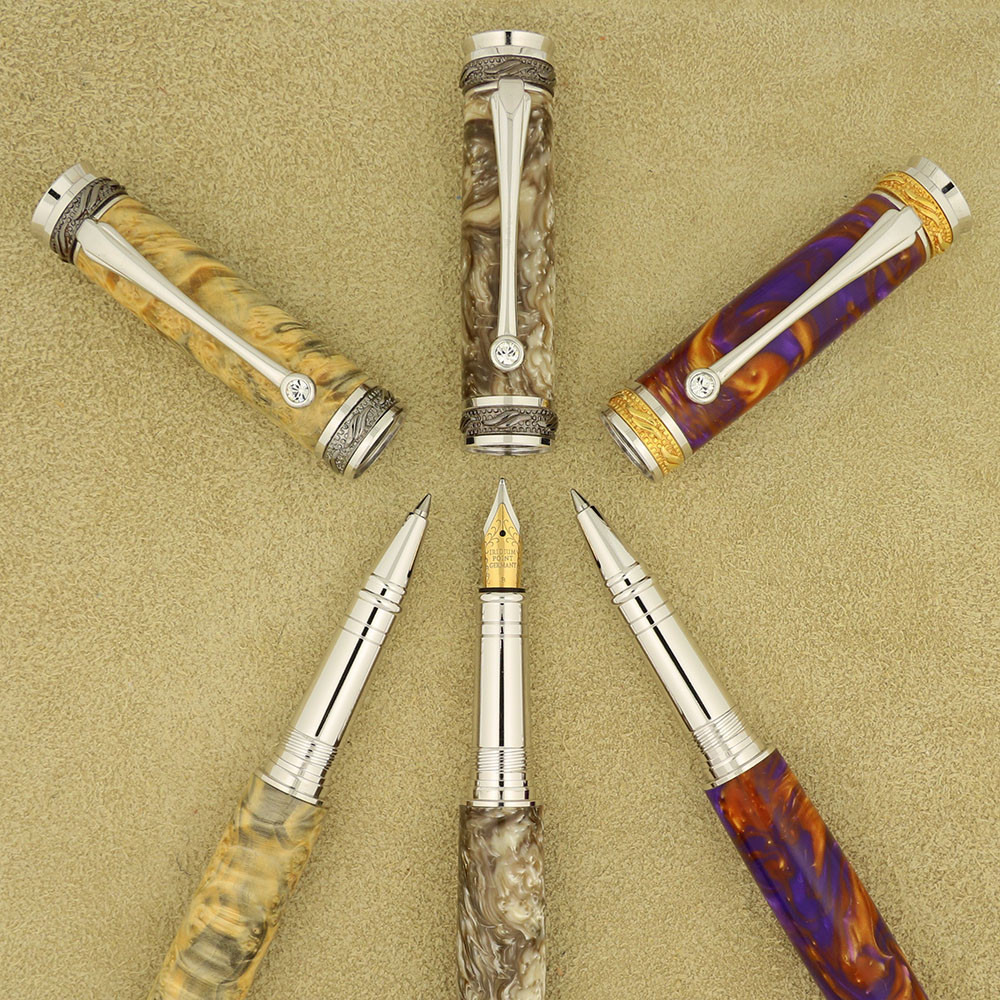 Three gold and chrome  pens with filigree are shown with the lids off, in different tones of burl wood. Each pen clip has a clear jewel on it.