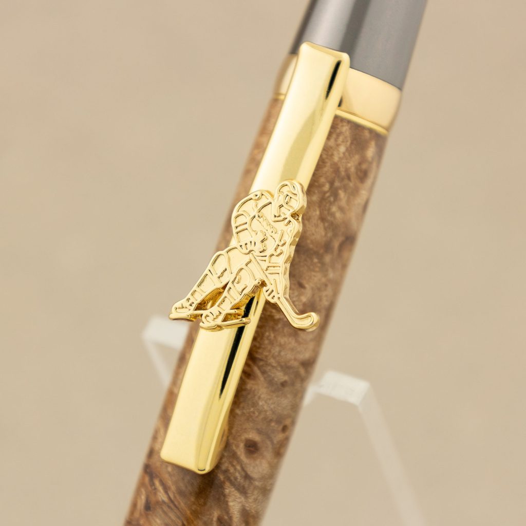 Close up of a gold pen clip with a hockey player on it.