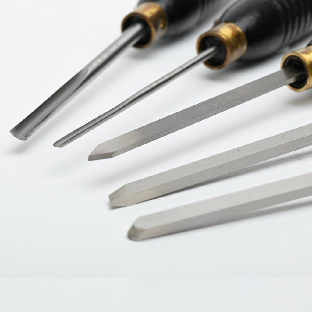 A set of five wood turning chisels with black wooden handles on a white background