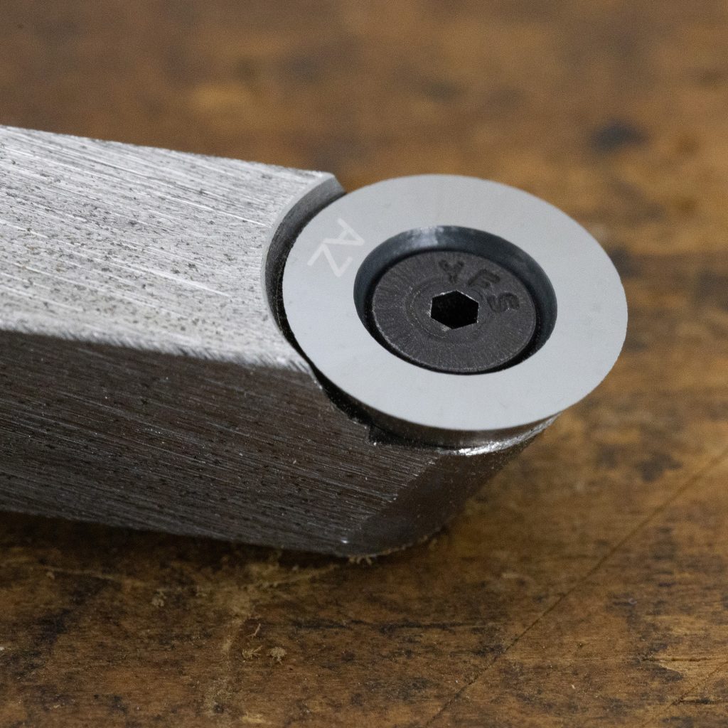 A closeup of a round tipped carbide chisel for woodturning on a wood background.