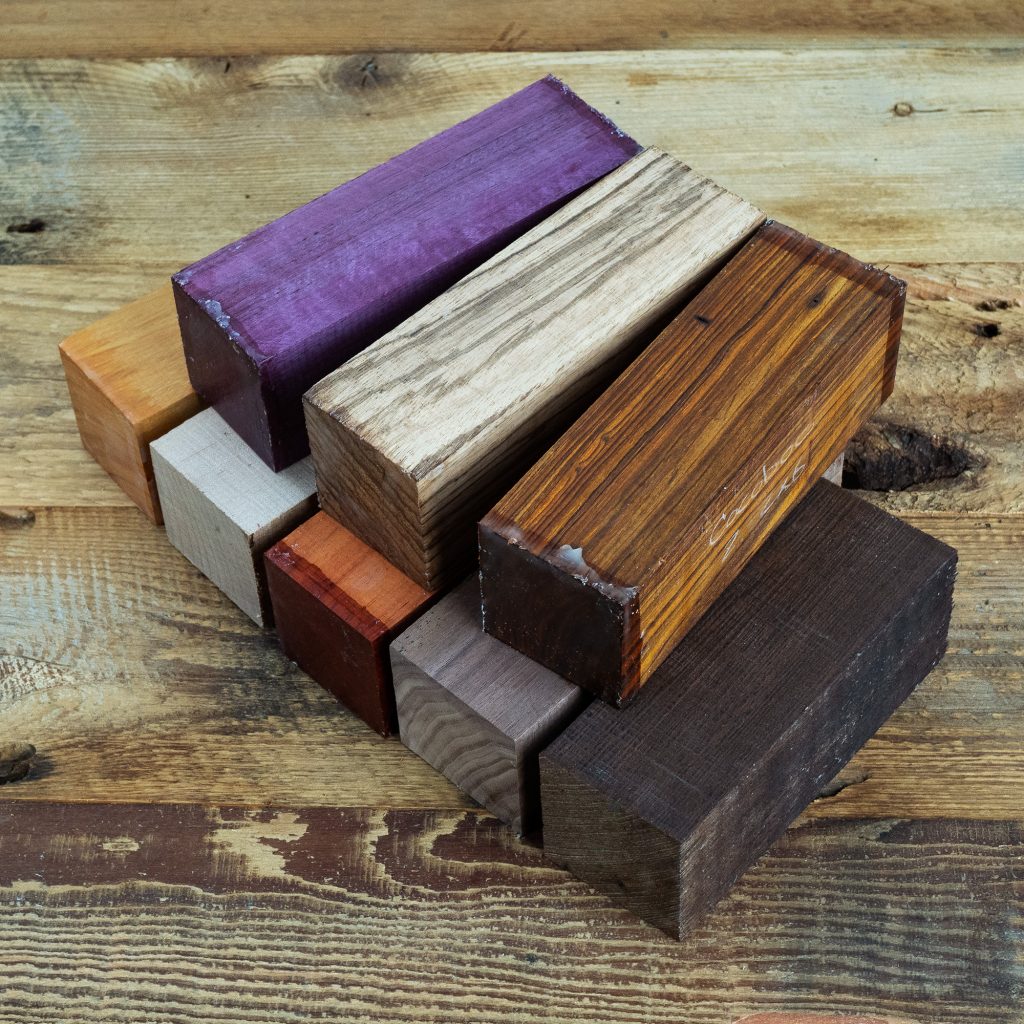 A selection of blocks of exotic wood in various colours on a distressed wood surface